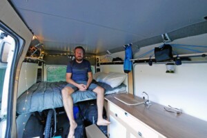 customer devin sitting on bed inside camper van