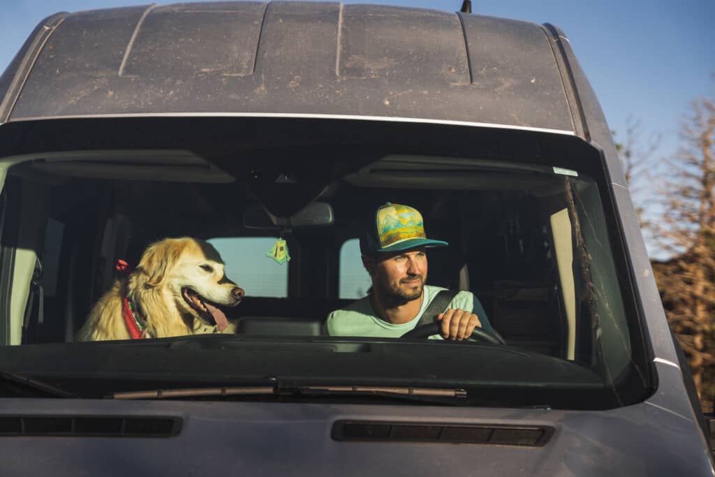 man driving a camper van with his dog