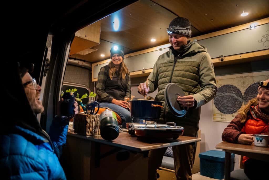 group of friends enjoying dinner in a camper van conversion