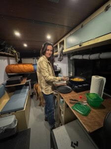 woman standing inside camper van cooking